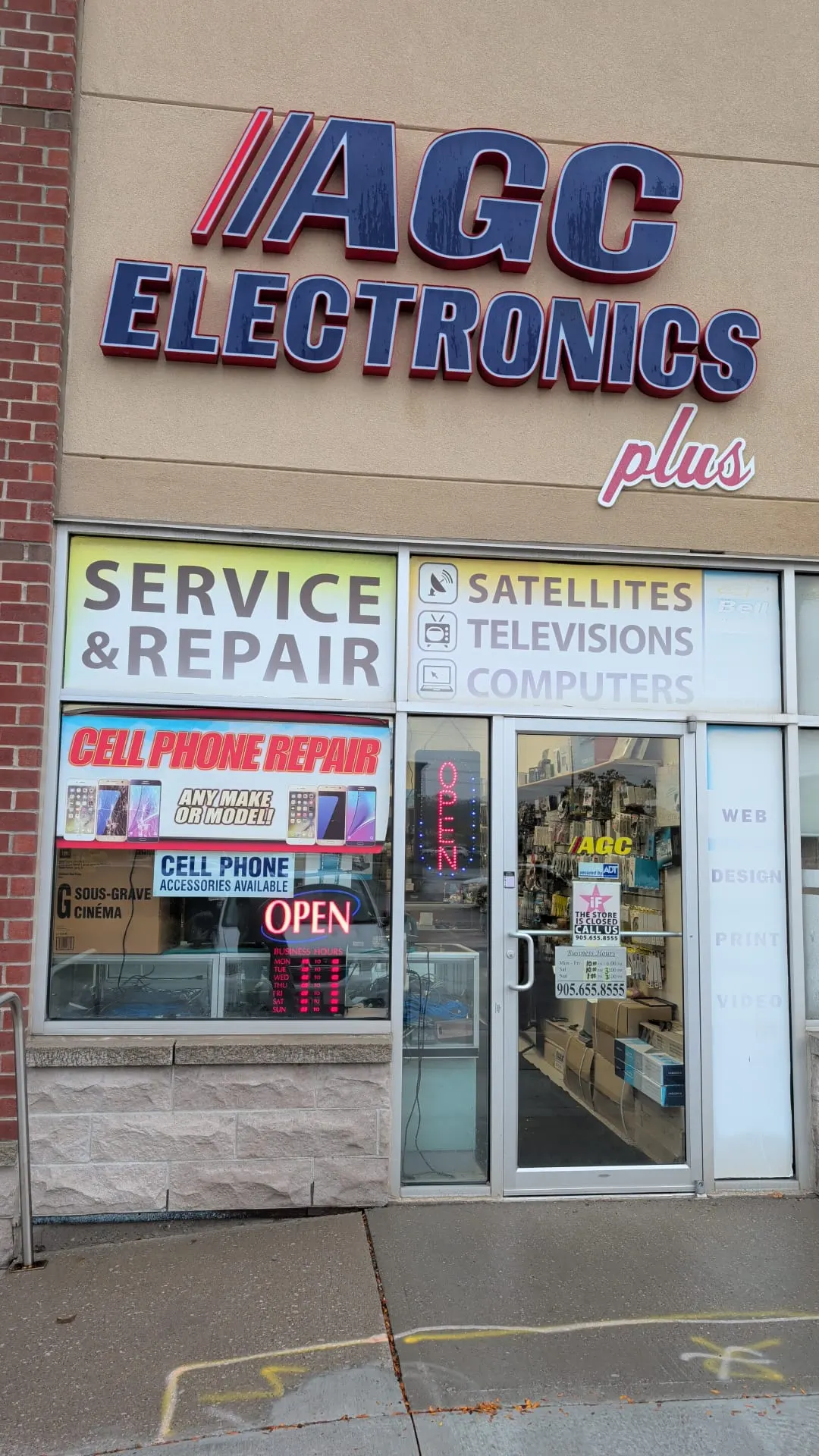 The AGC Electronics Plus storefront in the Thickson Mills plaza, Whitby, with Service and Repair and Cell Phone Repair signs in the window