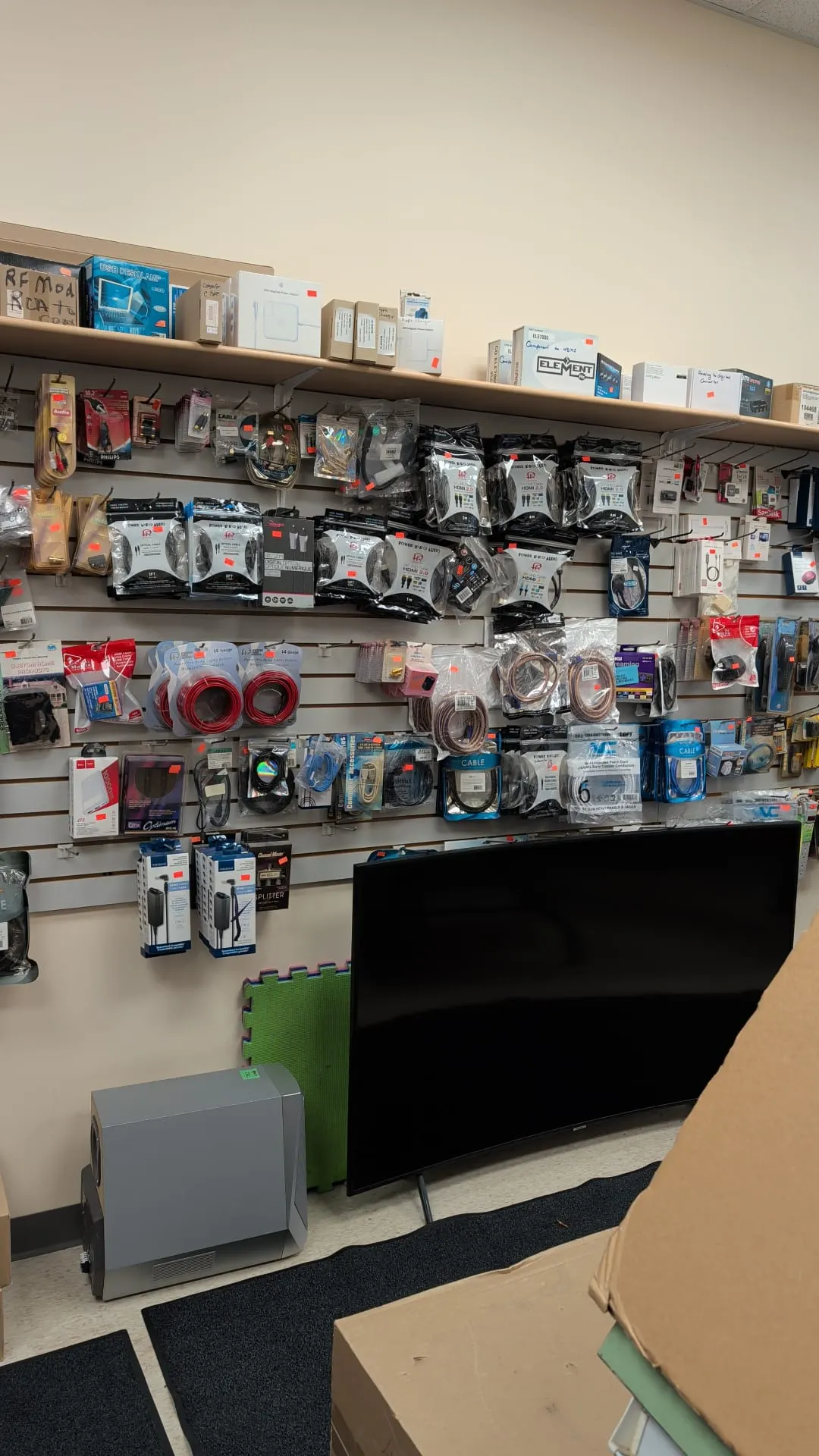 A wall of cables and adapters with a curved TV on display below