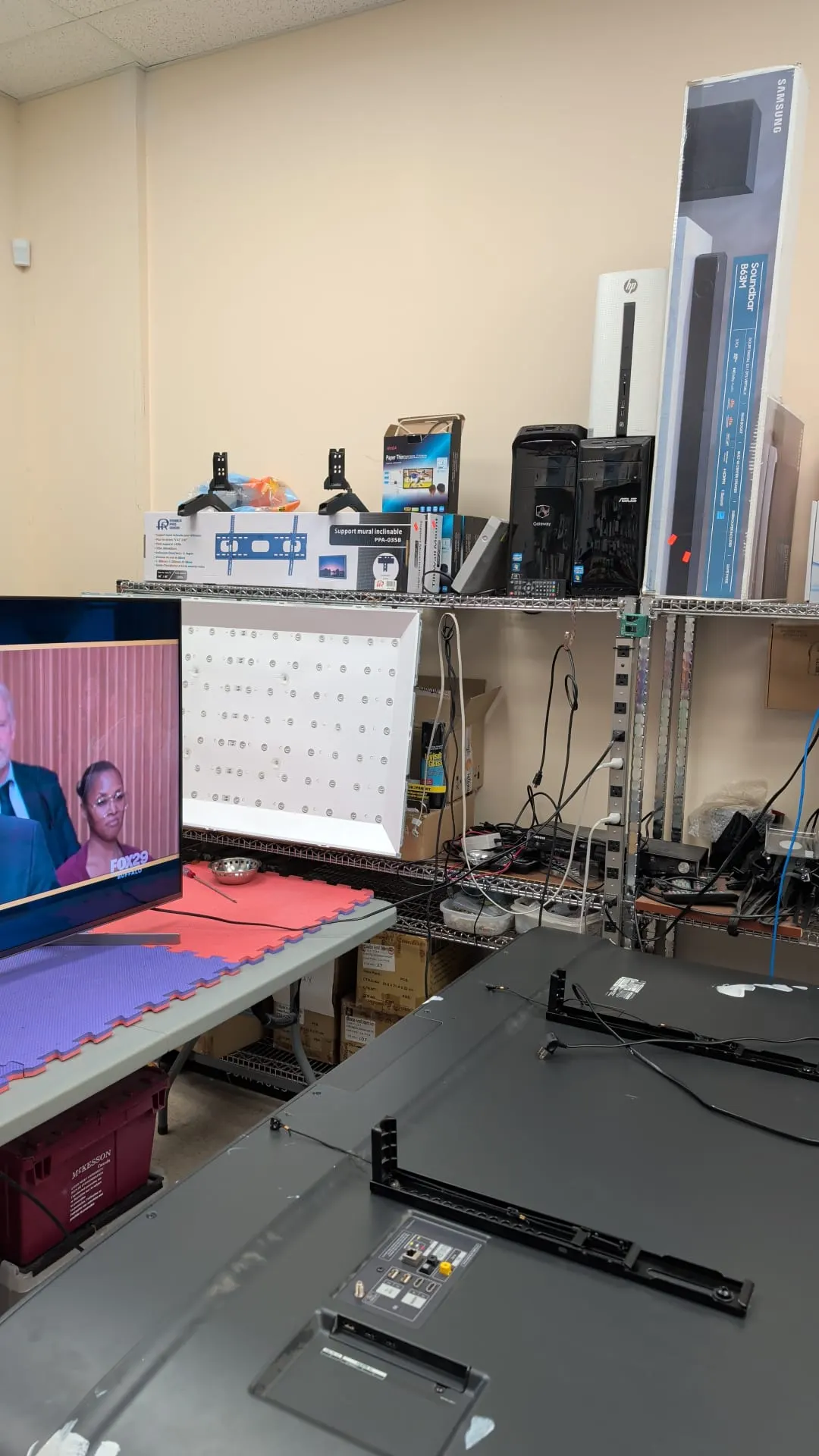 A large flat-screen TV lying face down on the repair bench with its back panel removed